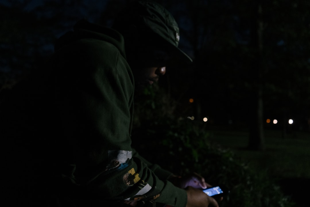 person in black and yellow jacket holding smartphone