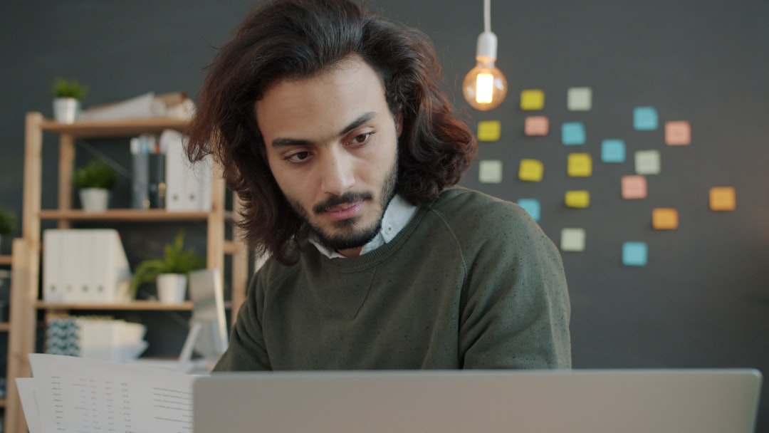 Man with long hair working on laptop in office