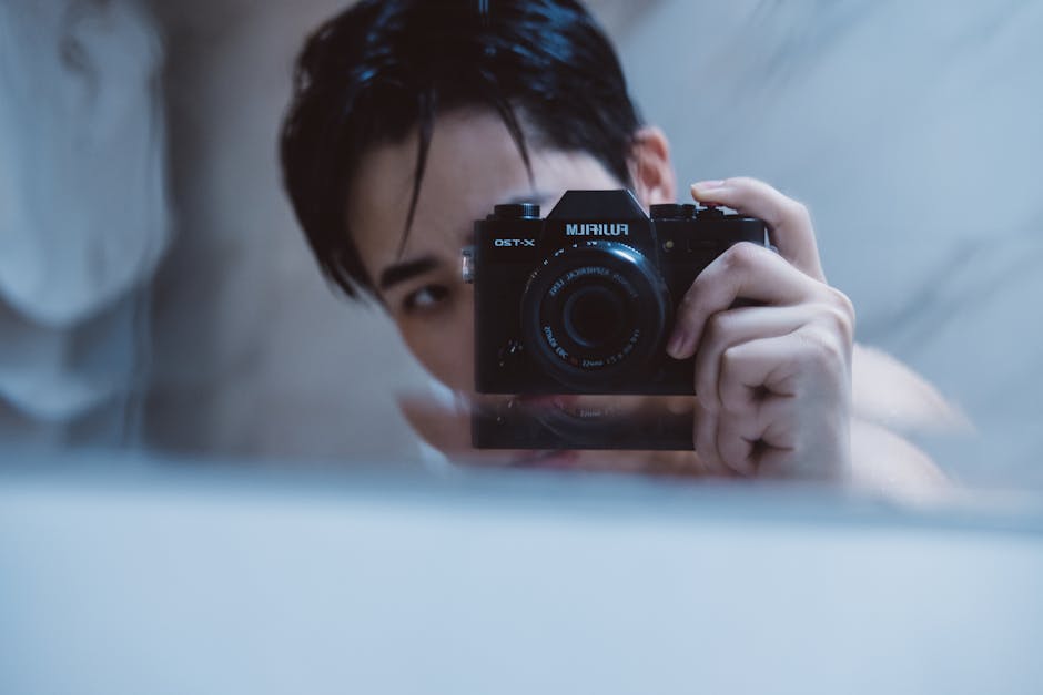 Close-up of a young man using a camera for a self-portrait indoors.