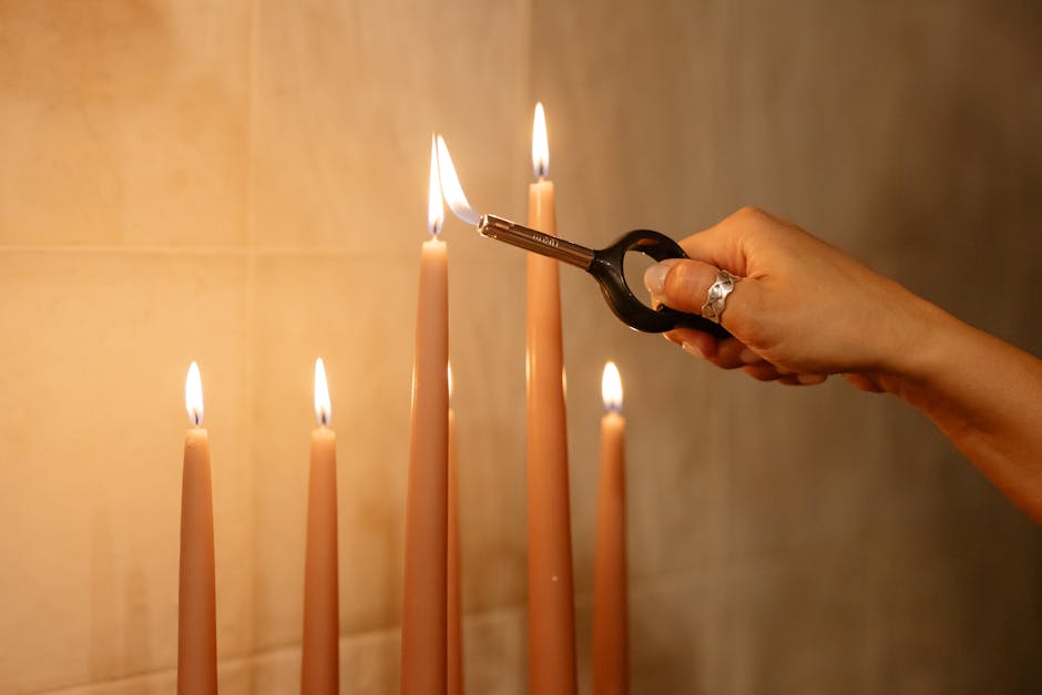 Elegant scene of hand lighting taper candles against a warm indoor background.