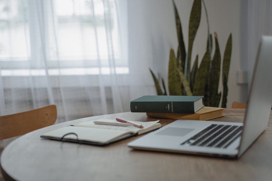 A tranquil indoor workspace featuring a laptop, books, and a notebook for studying or remote work.