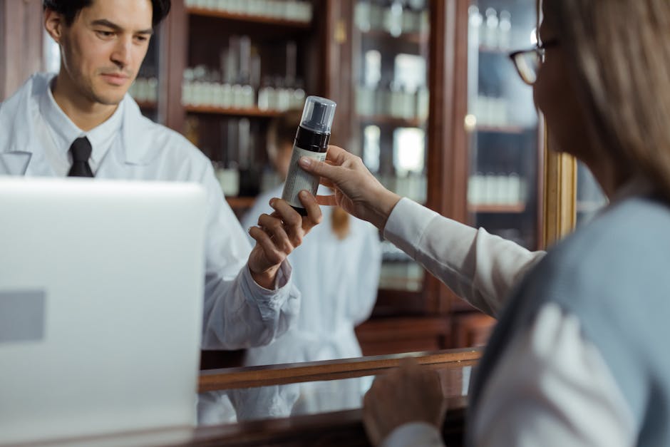 A pharmacist in a white uniform hands medication to a customer across the counter.
