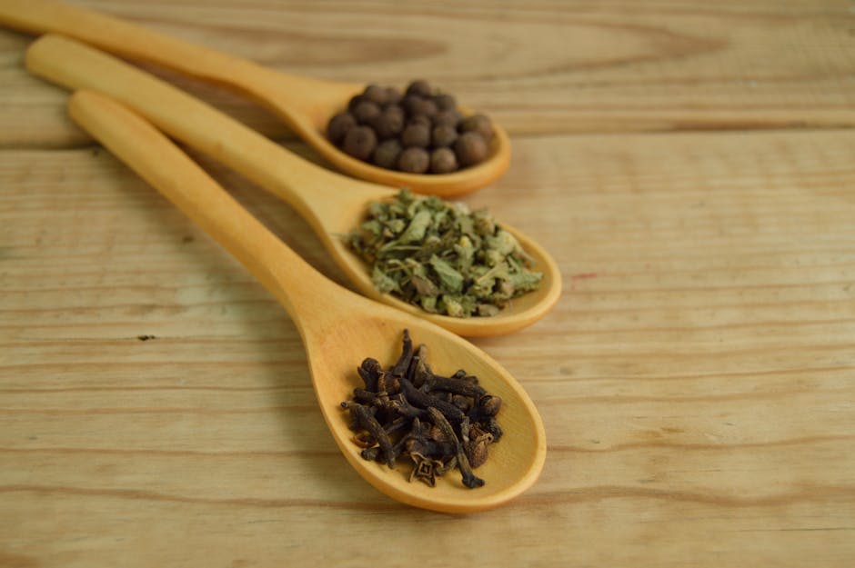 Close-up of wooden spoons on a table filled with aromatic spices.