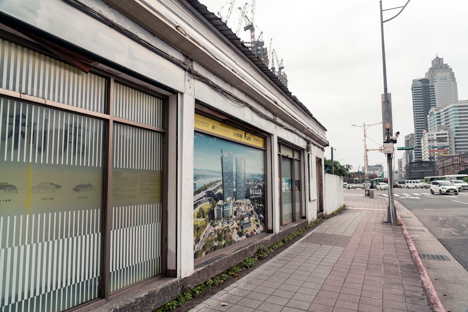 A city street in Taipei featuring modern buildings and an old construction site, merging tradition with urban development.