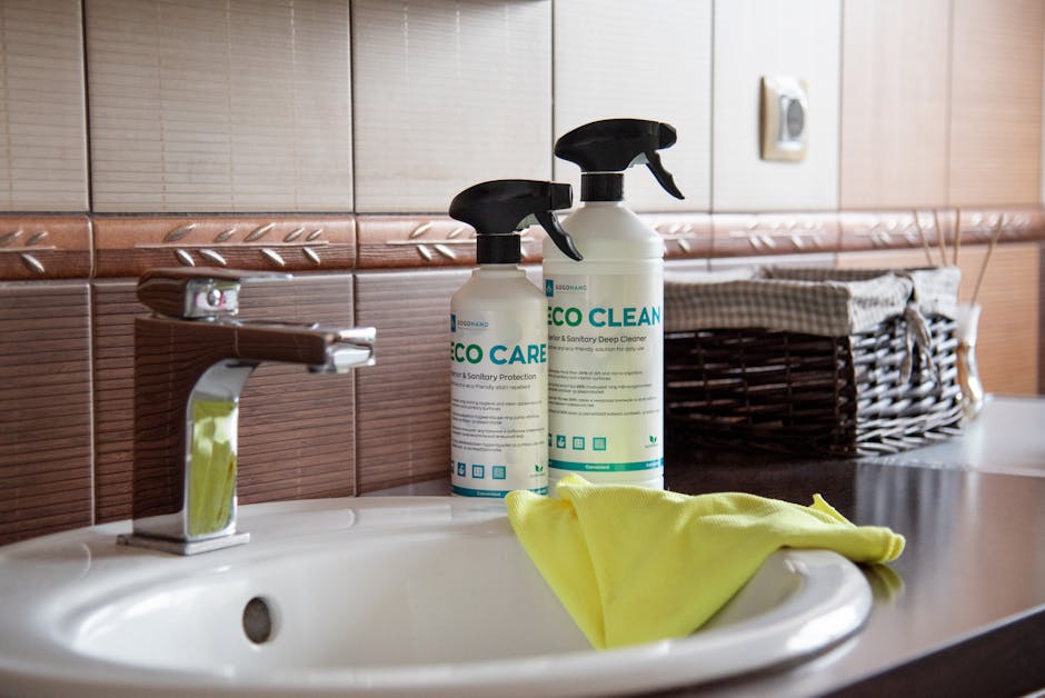Eco-friendly cleaning products displayed on a bathroom sink with tiles and a basket.