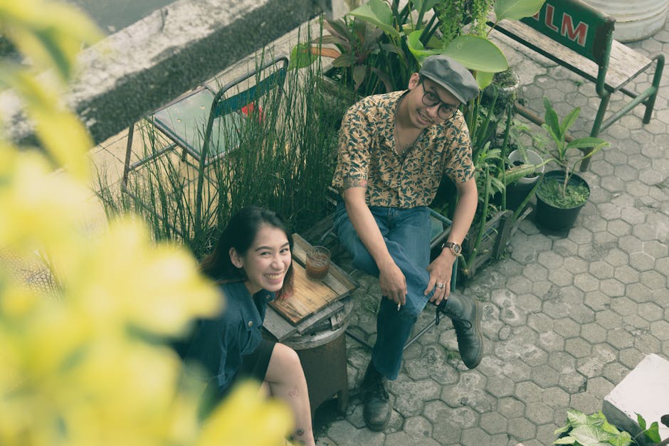 A happy man and woman sitting in an outdoor garden, surrounded by green plants and enjoying a break.