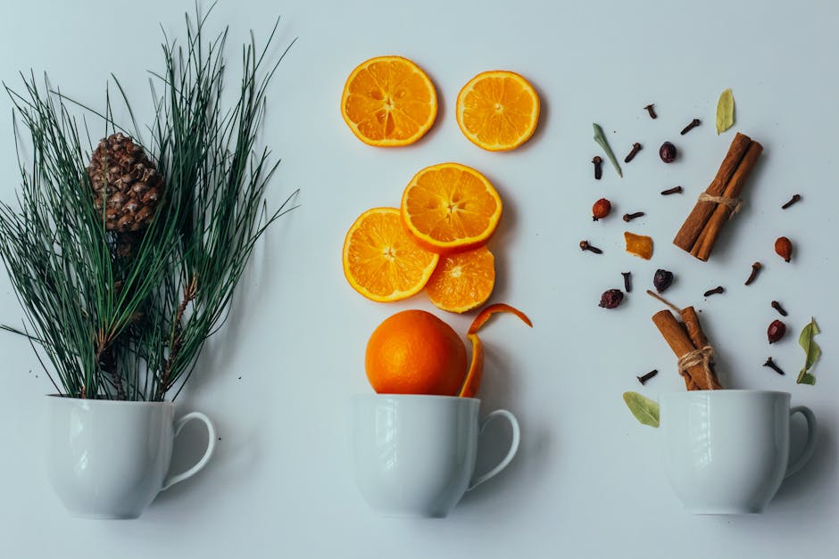 Flat lay showcasing winter motifs with pine, orange slices, and spices in cups.