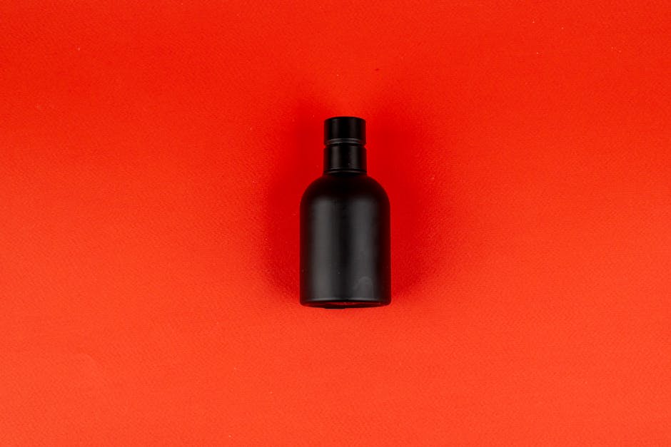Elegant matte black perfume bottle on vibrant red surface, ideal for product display.