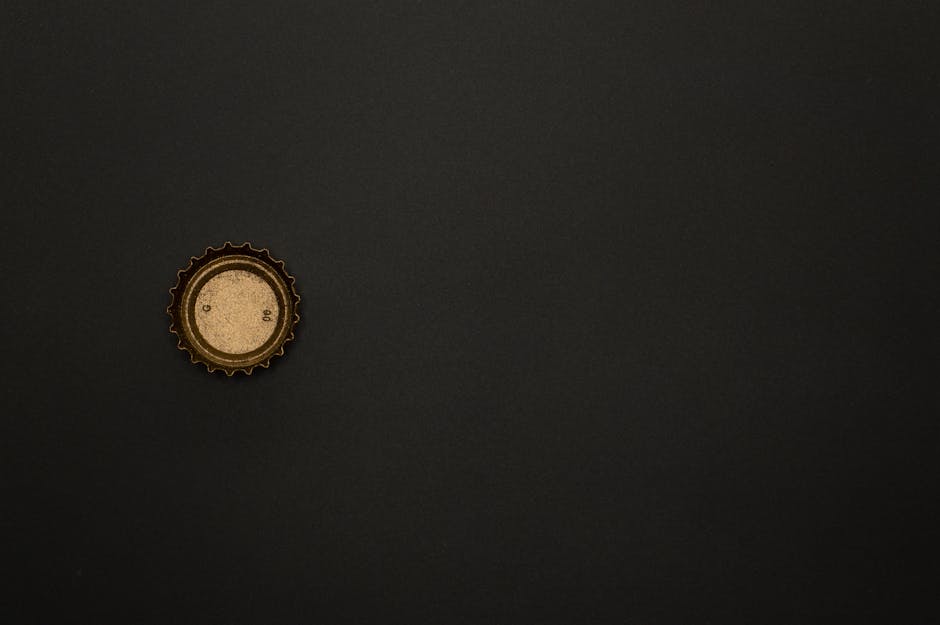 Minimalist image of a golden bottle cap on a dark surface, providing ample copy space.