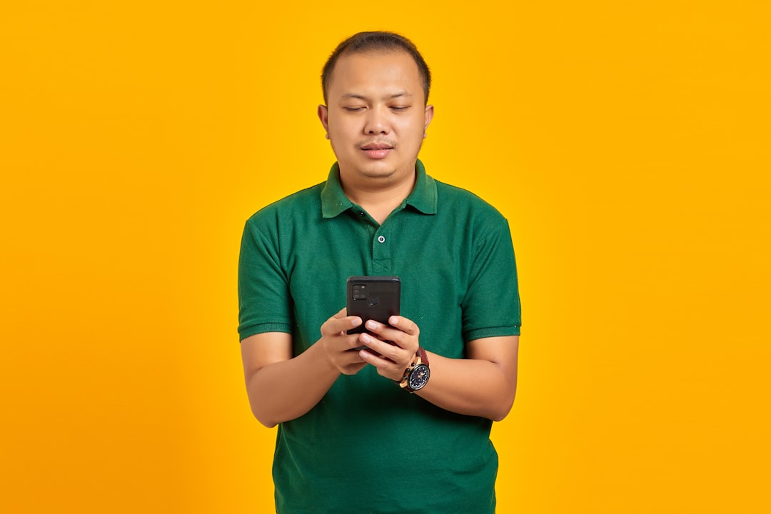 a man in a green shirt looking at a cell phone