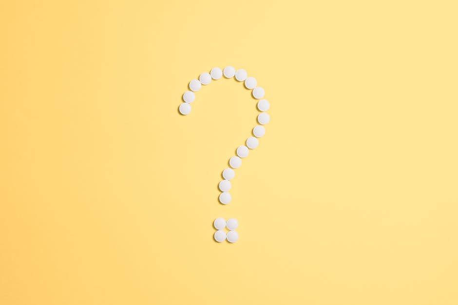 White pills arranged into a question mark shape on a vibrant yellow background.