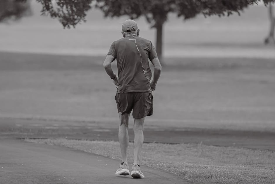 A senior man jogs alone in a serene park in Stamford, Connecticut, captured at dawn.