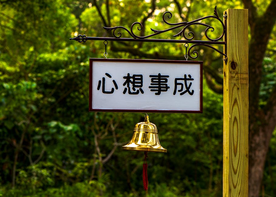 Outdoor signage with a golden bell in a lush Taipei park setting, conveying tranquility.