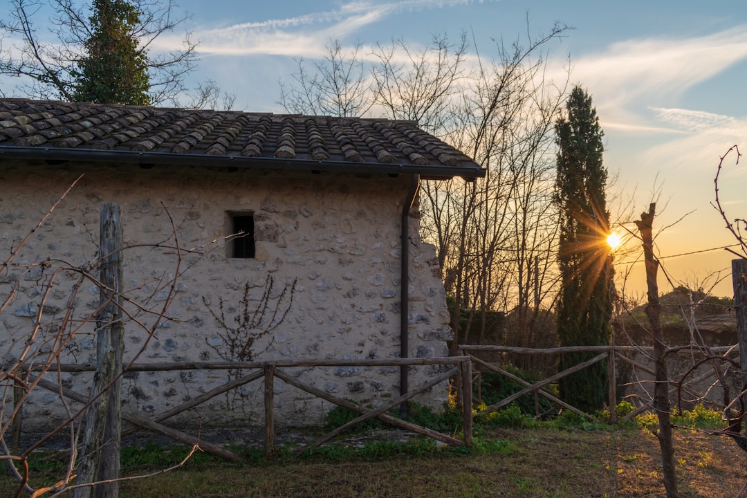 Stone building with sunset behind trees.