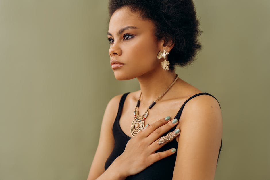 A stylish woman in elegant jewelry poses against a neutral background, exuding confidence.