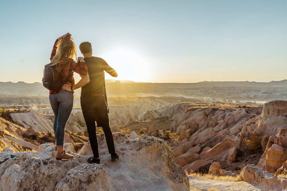 A couple enjoys a breathtaking sunrise view over the unique rock formations of Cappadocia, Turkey.