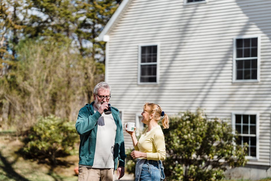 Two adults enjoying coffee and conversation outside a house in a garden setting.